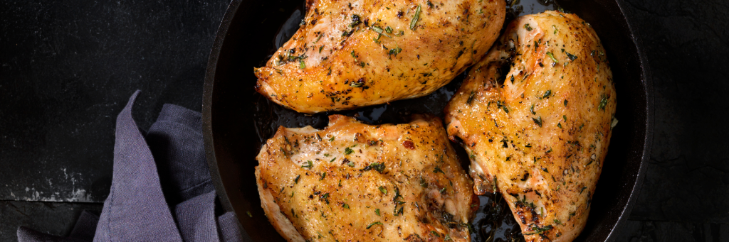 Shot of three herb seasoned chicken breasts baked in a cast-iron skillet.
