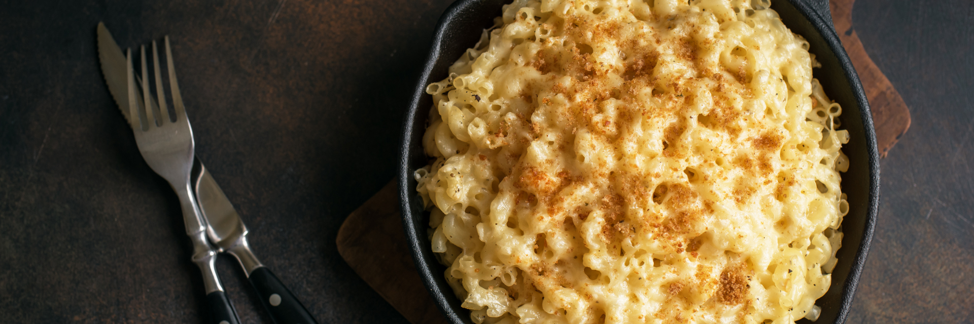 Wide shot of baked macaroni and cheese in a cast-iron skillet.