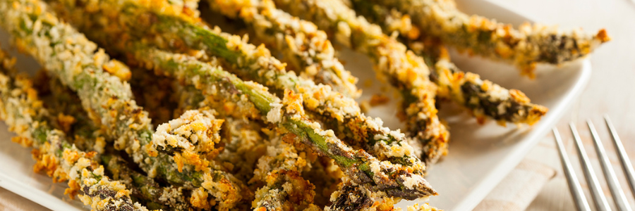 Close up of cooked asparagus spears covered in breadcrumbs on a square white plate.