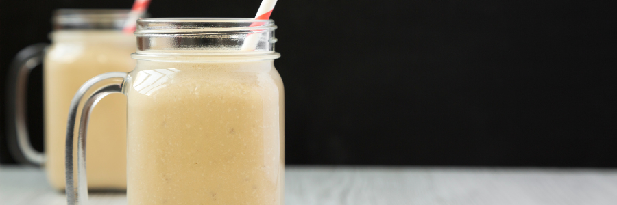 Old fashioned mason jar filled with a light colored banana smoothie.