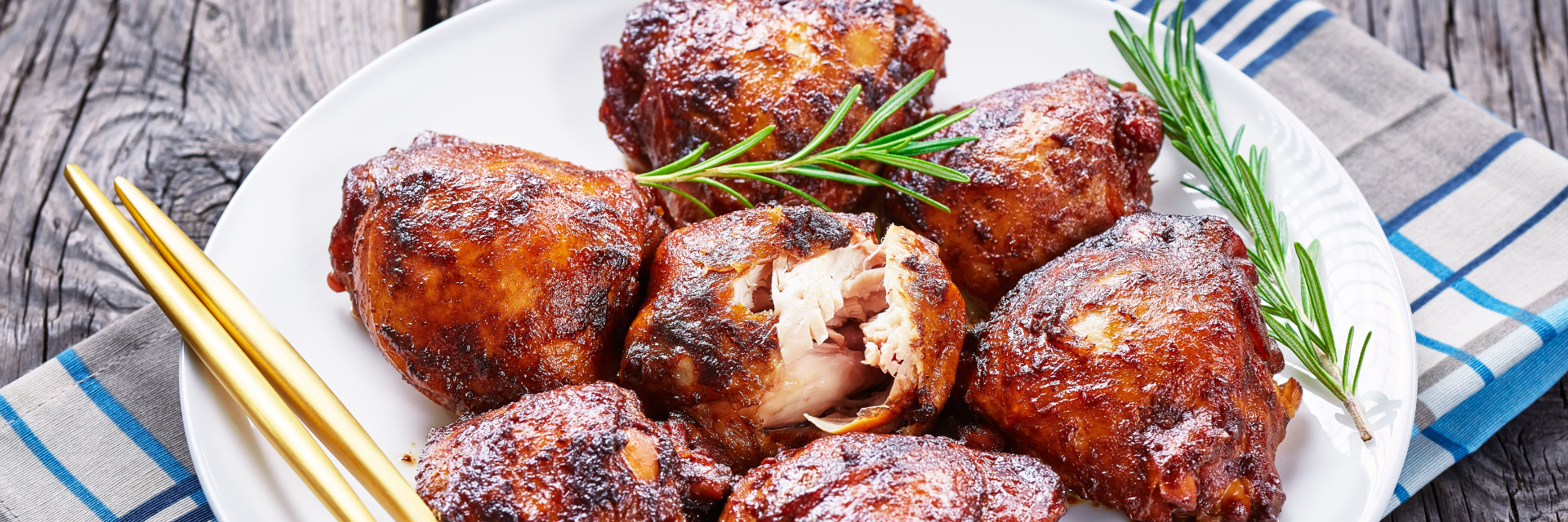 Delicious looking Southern Barbecue Chicken with a nice layer of barbecue on the outside and tender chicken on the inside. Everything is placed on a white plate, sitting on top of a blue, gray and white stripped towel on weathered wood.