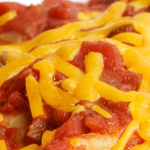 Close up view of whole-wheat tortillas topped with salsa and shredded cheddar cheese in a white casserole dish.