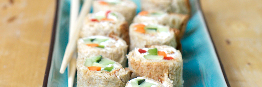 Close up view of a nine pieces of vegetable sushi filled with peppers and cream cheese on a long plate with chop sticks resting on the edge.