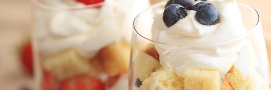 Close up shot of a glass layered with fruit, angel food cake, and yogurt.