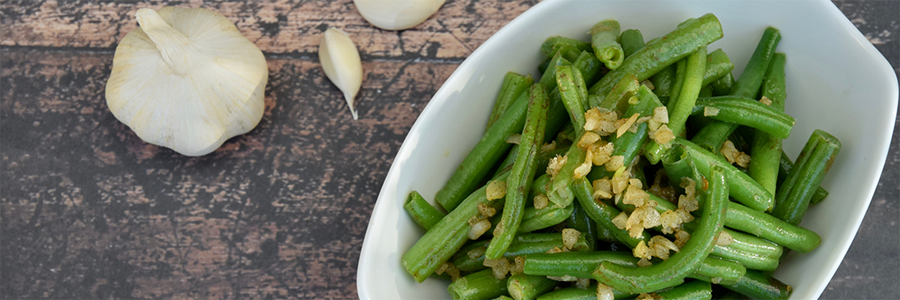 Wide shot of a platter with green beans and garlic.