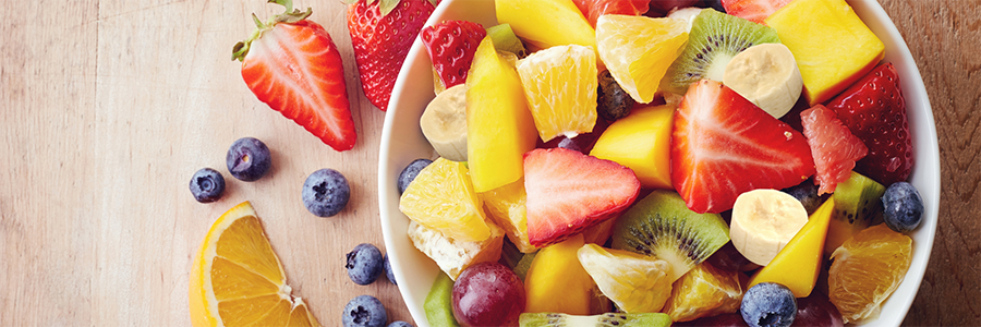 Close up shot of a bowl of fruit salad with strawberries, blueberries, mango, grapes, kiwi.