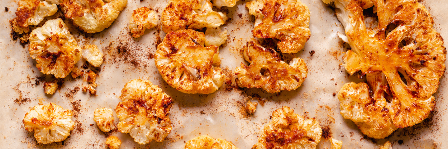 Roasted cauliflower florets on a parchment lined sheet pan.