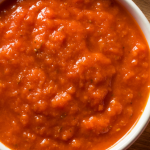 Red tomato sauce in a white bowl.