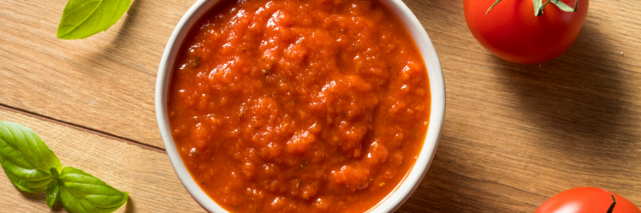 Red tomato sauce in a white bowl.