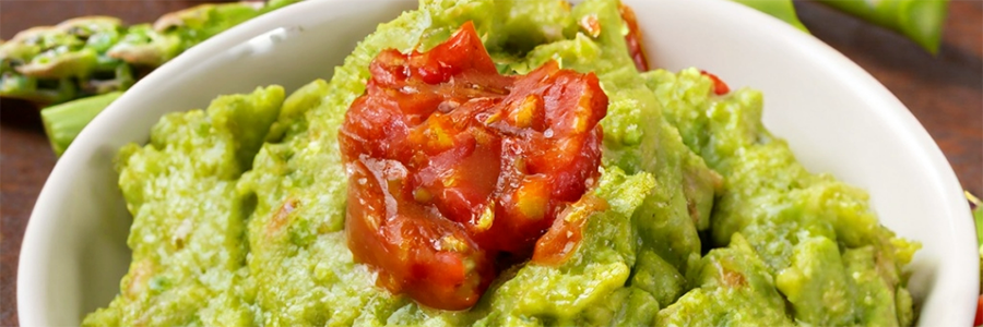 Close up shot of a small bowl of guacamole made with asparagus, onions, and tomato.