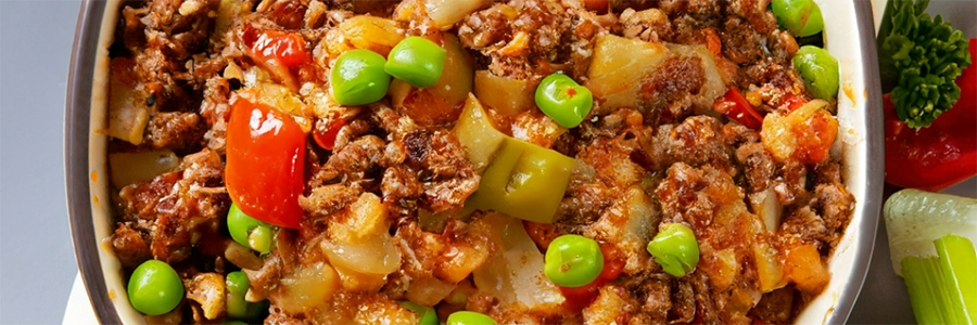 Close up of Beef & Vegetable Casserole in a pot with tomatoes, peas and other vegetables mixed in.