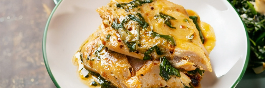 Shot of seasoned chicken breasts and spinach in a creamy sauce.