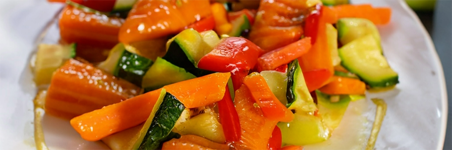 Close up shot of sliced veggies, including carrots and zucchini, coated in a sweet honey glaze.