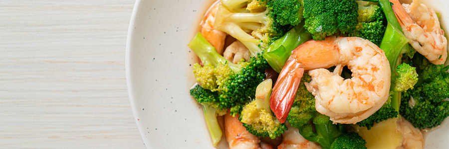 Close up shot of a plate with a stir fry with shrimp, broccoli, and other vegetables.