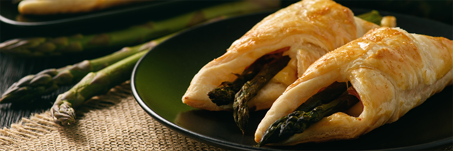 Wide shot of asparagus spears wrapped in flaky puff pastry.