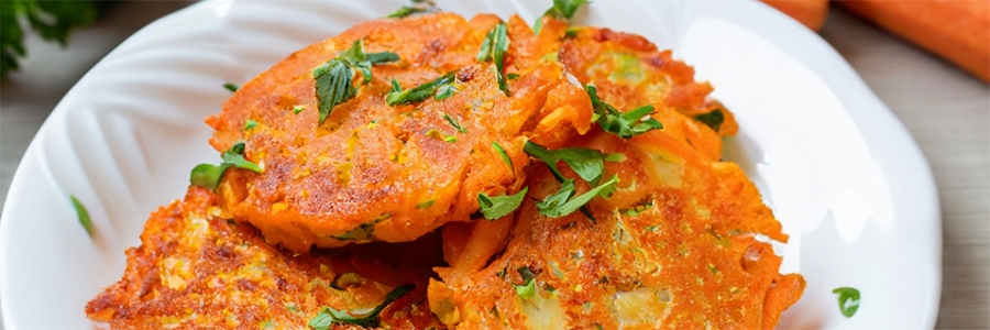 A plate of stacked carrot fritters stacked on a plate and garnished with fresh parsley.