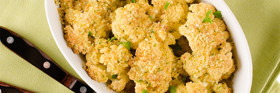 Close up shot of baked cauliflower coated in breadcrumbs and Parmesan. Garnished with parsley flakes.