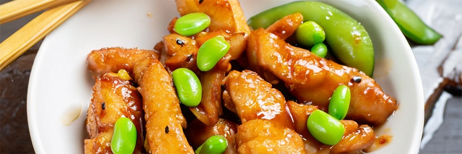 Shot of strips of chicken stir-fried with edamame in a honey, garlic, soy sauce.