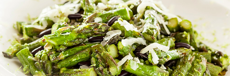 Close up shot of a salad with chopped asparagus and black beans. Salad is garnished with Parmesan.