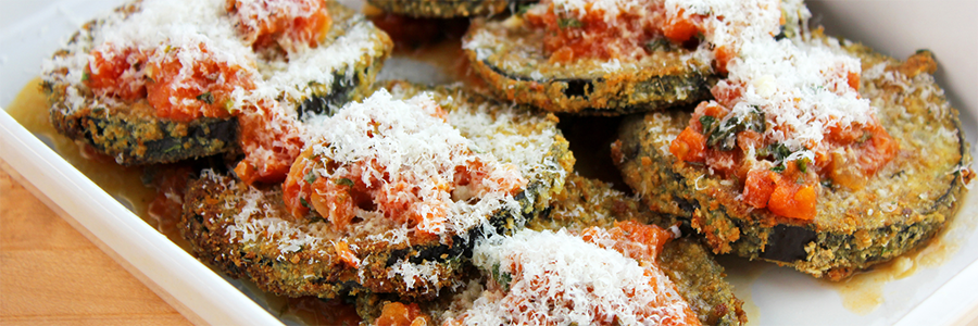 Close up shot of eggplant slices coated in breadcrumbs, topped with marinara sauce, and garnished with shredded mozzarella cheese.