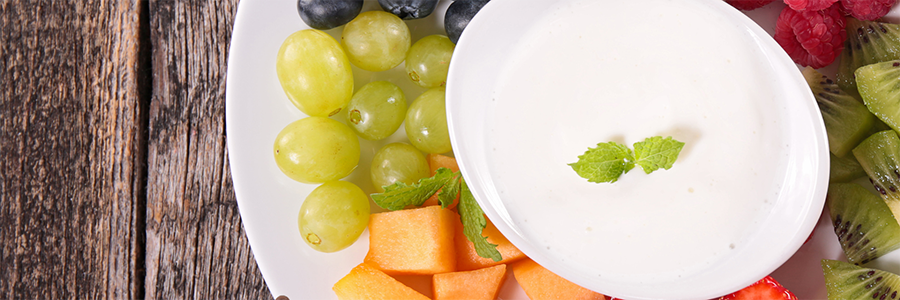 Close-up shot of a plate of assorted fruit with grapes, melon, blueberries, and kiwi.