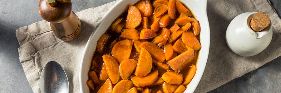 Close up shot of a casserole dish with sliced sweet potatoes baked with cinnamon and brown sugar.