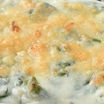 Close up of a casserole dish with a mixture of baked mashed potatoes and spinach, topped with melted mozzarella cheese.