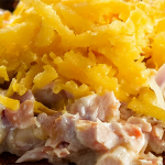 Shot of a toasted English muffin topped with tuna salad and garnished with melted cheddar cheese.