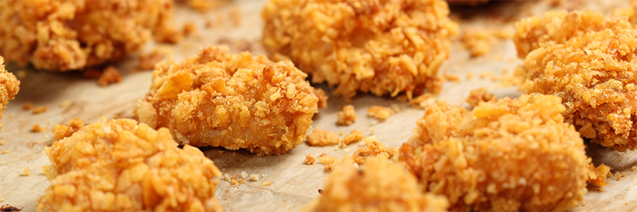 Wide shot of crispy chicken nuggets on a baking sheet.