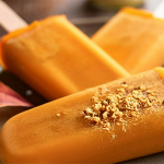 Wide shot of three pumpkin popsicles on a plate.
