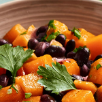 Shot of a bowl with sautéed squash and black beans, garnished with sprigs of parsley.