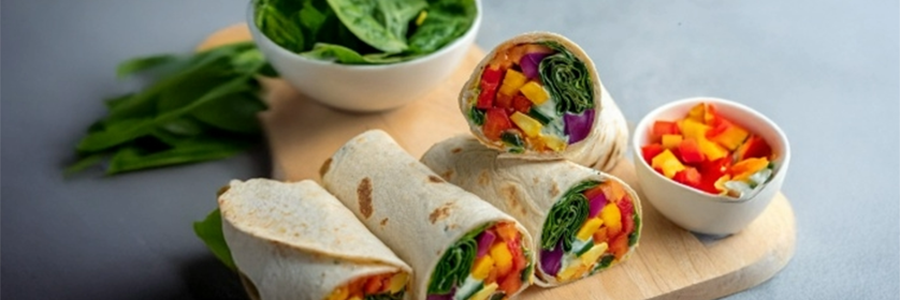 Wide shot of colorful veggie wraps displayed on a cutting board.