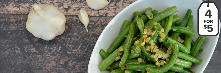 overhead shot of a bowl of green beans topped with minced garlic.