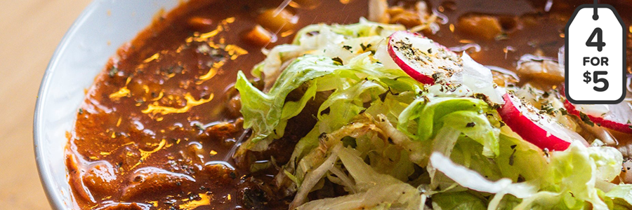 Close up shot of white bowl of chili garnished with sliced radishes and slivered lettuce.