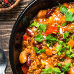 Bowl of chili with white and red beans, garnished with cilantro