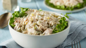 Bowl of creamy chicken salad on a bed of lettuce.