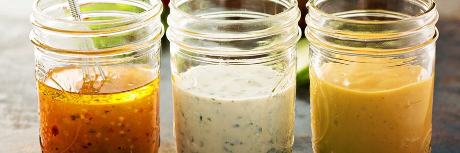 Three small mason jars with dressings and marinades in them