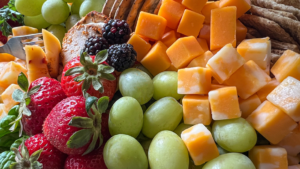 Close up shot of a grazing board with strawberries, grapes, crackers and an assortment of cheeses.
