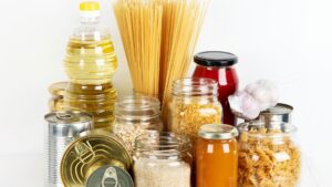 Collection of common pantry items like canned goods, jarred sauces, oats, rice and pasta.