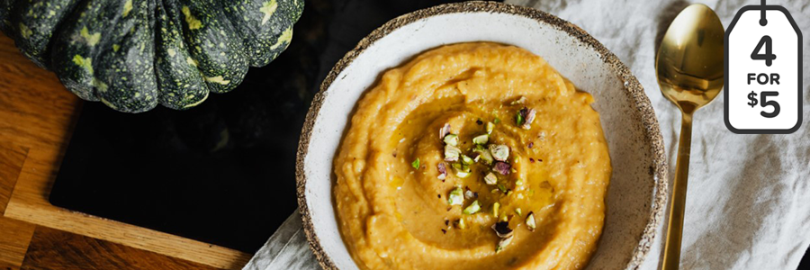 Overhead shot of a bowl of pumpkin dip. Displayed next to a green pumpkin on a table.
