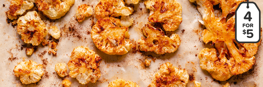 Roasted cauliflower florets on a parchment lined sheet pan.