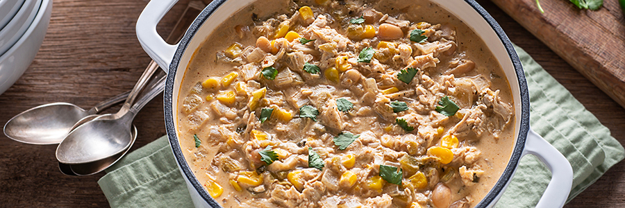 Shot of a pot of white chicken chili with corn and white beans. Garnished with cilantro.