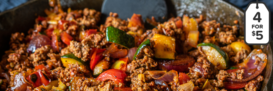 Close up shot of a cast-iron skillet with ground turkey and sauteed peppers and onions.