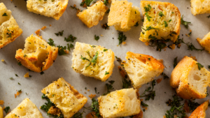 Cubed bread on parchment papers, garnished with parsley.