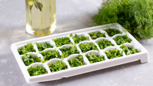 An ice tray with chopped parsley ready to be frozen.
