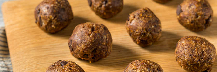 energy balls lined up in rows on a wooden cutting board.