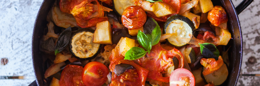black pan full of sauteed vegetables, like tomatoes, zucchini and potatoes