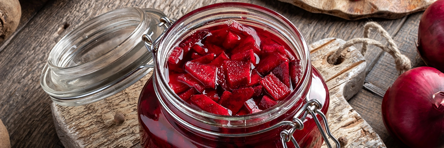 Close up shot of a lidded glass jar filled with pickled beets.