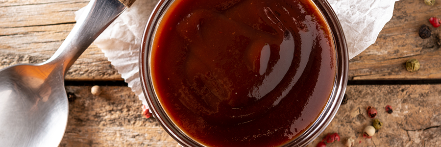 Overhead shot of a bowl of BBQ sauce on a table.