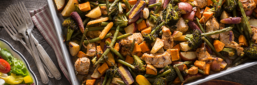 Overhead shot of a baking sheet with an assortment of chopped vegetables and chicken.